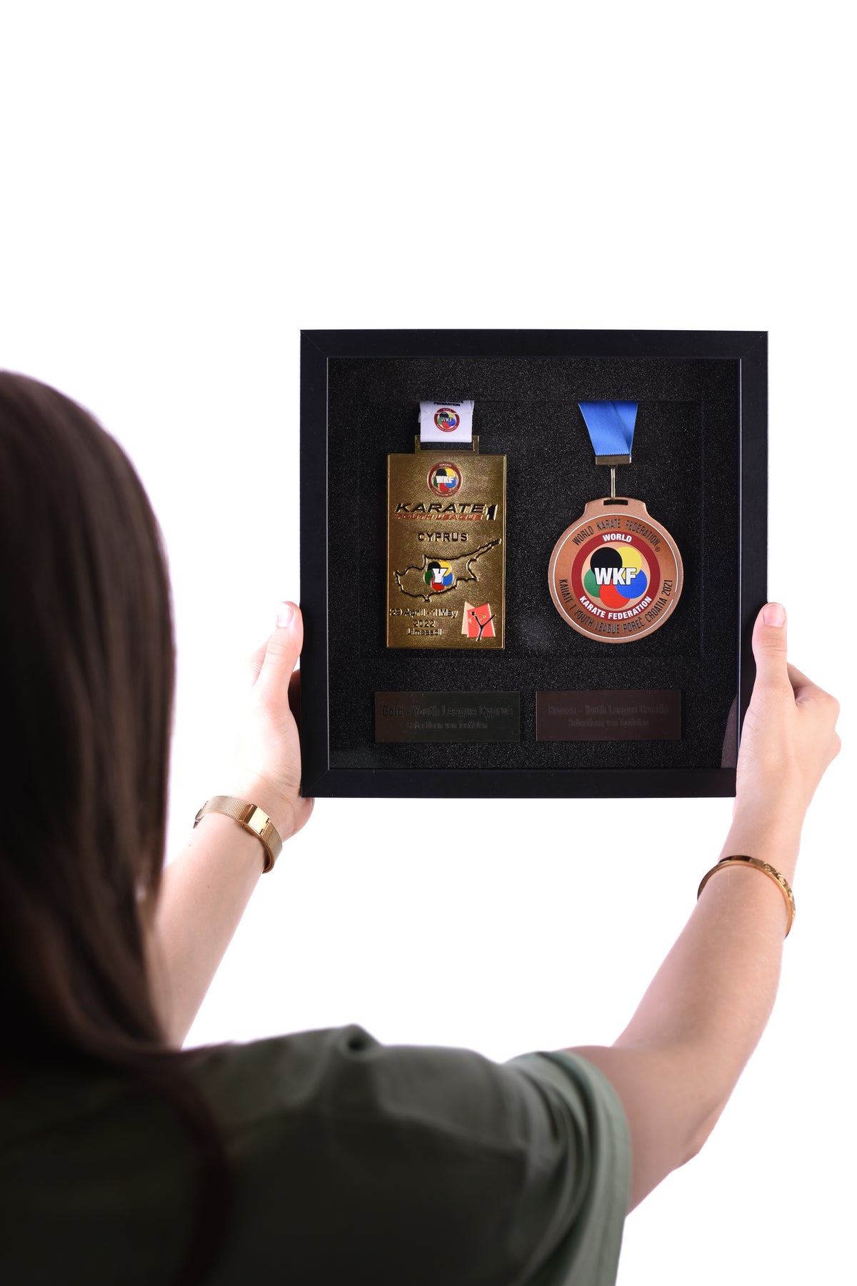 Woman holding a double medal frame with two karate medals and engraved nameplates